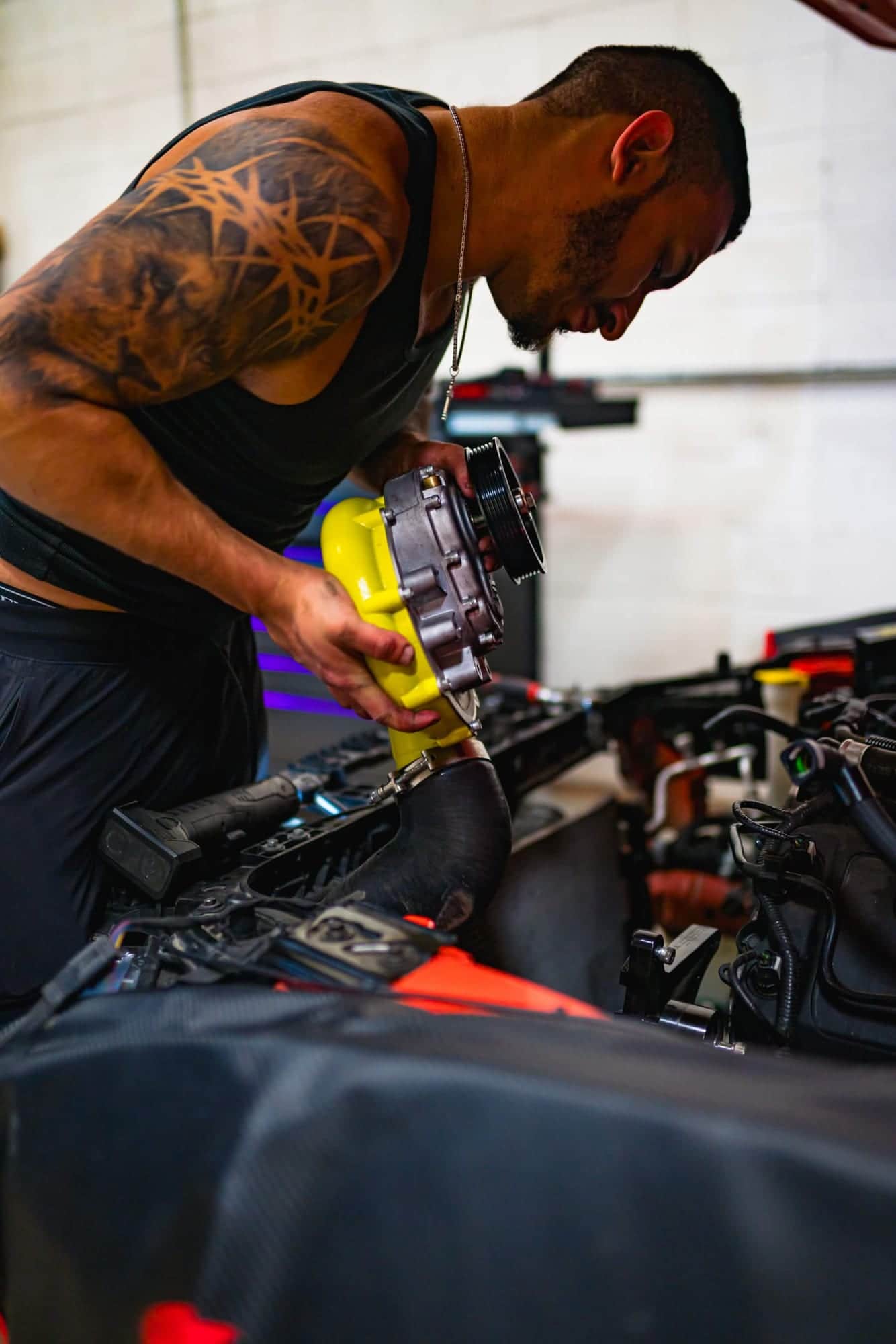Norik lowering a supercharger into an engine bay