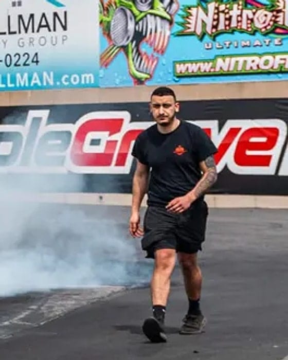 Norik, founder of Noro Performance, walking back down the strip at Maple Grove Raceway as tyre smoke clears behind him